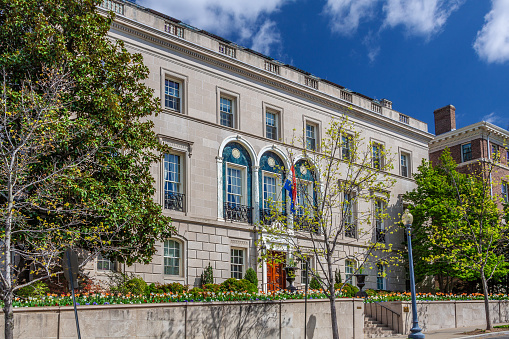 The Embassy of  Luxembourg, Embassy Row Neighborhood, Washington DC, USA.  Luxembourg national Flag, Green Trees, Flowers and Blue Sky with Clouds are in the image.