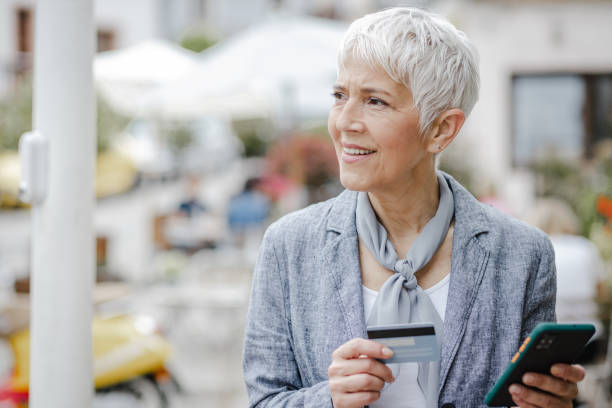istock Senior woman doing e-commerce activity while walking on the street 1340294085