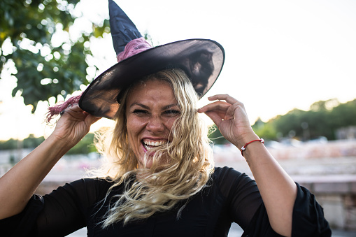 A happy young woman dressed as a witch is laughing on Halloween