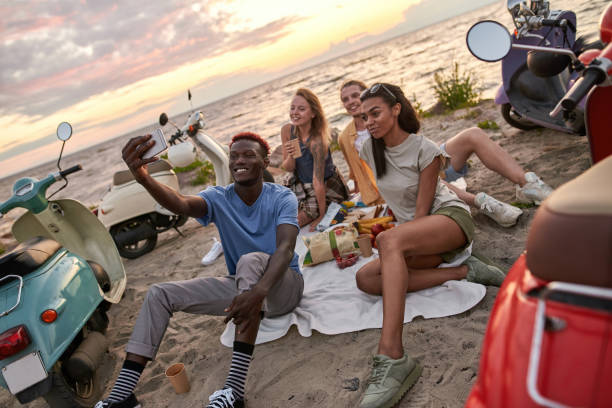 istock Cheerful diverse young people smiling while taking selfie, having picnic, spending time together on the beach 1340297259