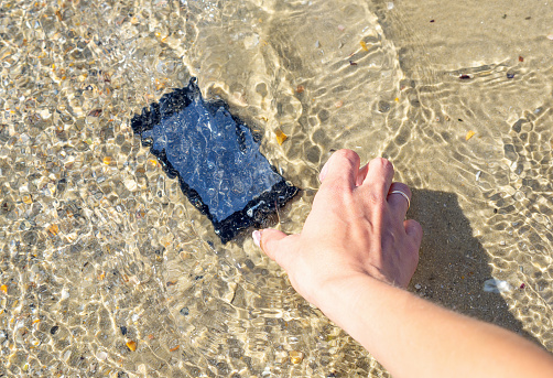 Lost and found accessories or property on vacation time, travel insurance, drowned smartphone repair- concept image.