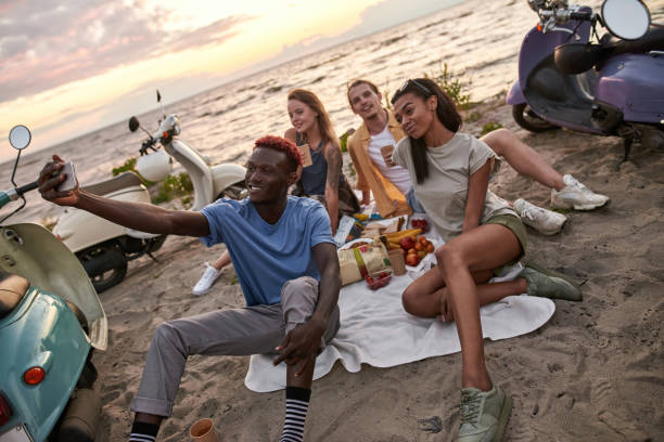 istock Happy diverse young people smiling while taking selfie, having picnic, spending time together on the beach 1340298263