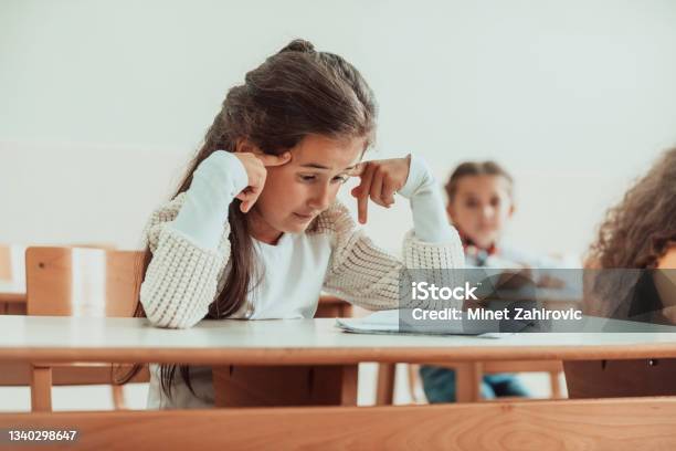 The Girl Sitting Confusedly With Her Hands On Her Head In The School Desk And Attends Classes Selective Focus Stock Photo - Download Image Now