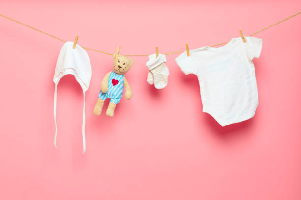 istock Baby clothes on a clothesline on pink background - Image 1340299618