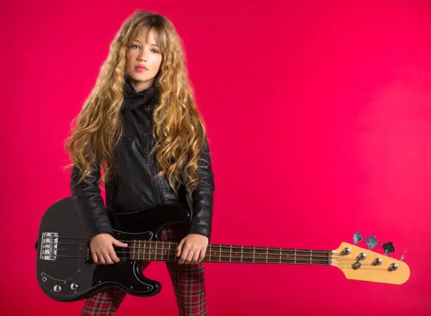 Blond Rock and roll girl bass guitar player on red background