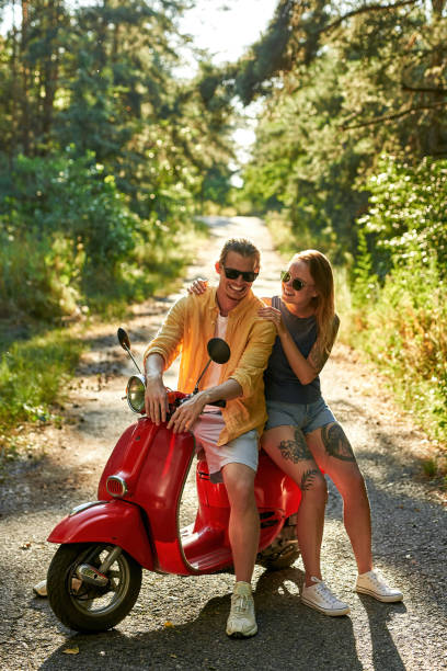 jeune couple caucasien heureux en scooter - motorcycle motor scooter couple young adult photos et images de collection