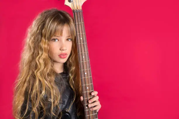Blond Rock and roll girl bass guitar player portrait on red background