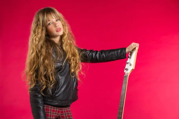 Blond Rock and roll girl bass guitar player portrait on red background