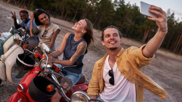 istock Cheerful young people, motorcycle riders posing while taking a selfie together, sitting on scooters outside the city 1340301741