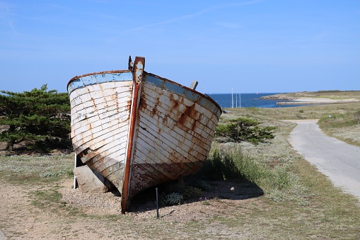 Old boat placed on a path of the island of Hoedic in Brittany in Morbihan and the bay of Quiberon l