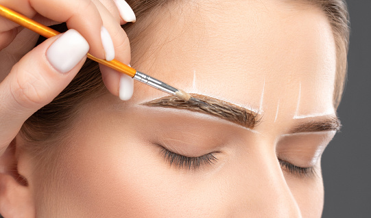 El artista de maquillaje hace marcas con lápiz blanco para cejas y pinta cejas. Maquillaje profesional y cuidado facial. photo