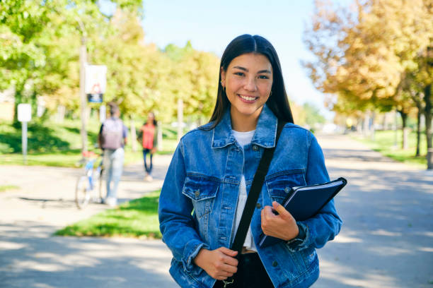 College Student on Campus A young woman college student, standing on campus. shoulder bag stock pictures, royalty-free photos & images