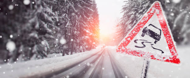 warning sign about the risk of slipping in the case of black ice on the street - on the snowy road - skidding bend danger curve imagens e fotografias de stock