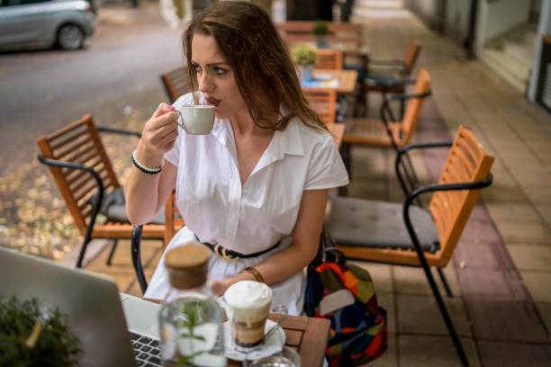 istock Businesswoman using laptop while enjoying work at cafe table with cup of coffee 1340312985