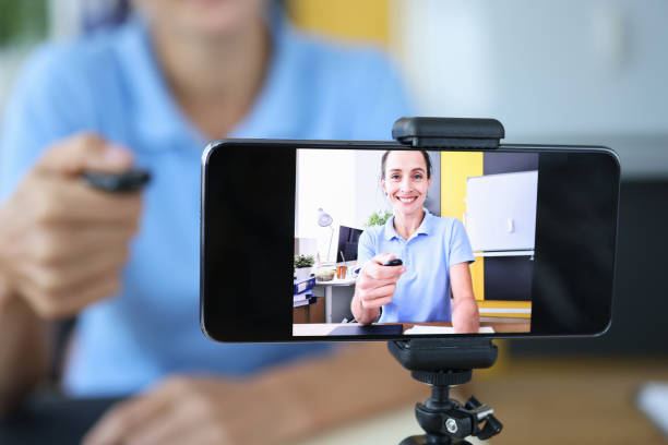 istock Woman with remote control launching tripod to record video on mobile phone 1340315734