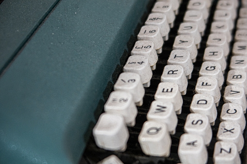 A classic style typewriter which is placed on working desk. Equipment object photo. Close-up and selective focus.