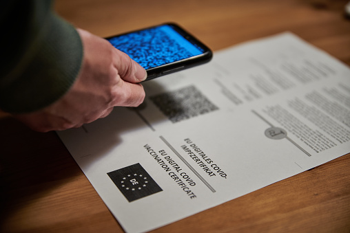 Person scanning the digital covid 19 certificate. Person scanning the QR code of a vaccination certificate.