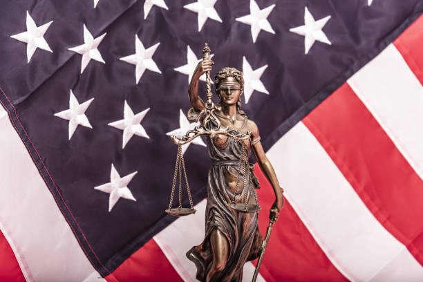 la estatua de la justicia themis o iustitia, la diosa de la justicia con los ojos vendados contra una bandera de los estados unidos de américa, como concepto jurídico - iustitia fotografías e imágenes de stock