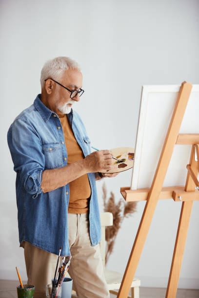 istock Senior artist painting on canvas at his home studio. 1340320444