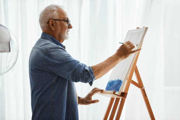 istock Mature man creating a new painting on canvas at home. 1340320446