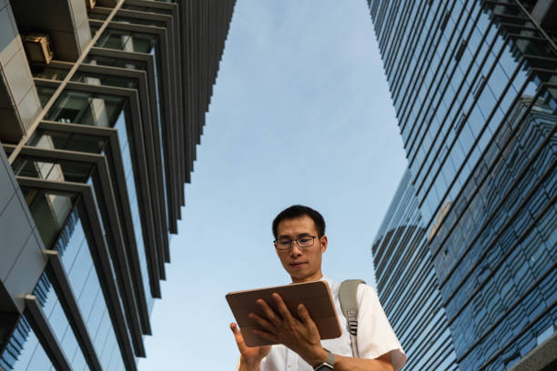 istock An Asian male businessman using a tablet under the office building 1340340056