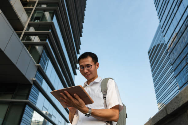 istock An Asian male businessman using a tablet under the office building 1340340095