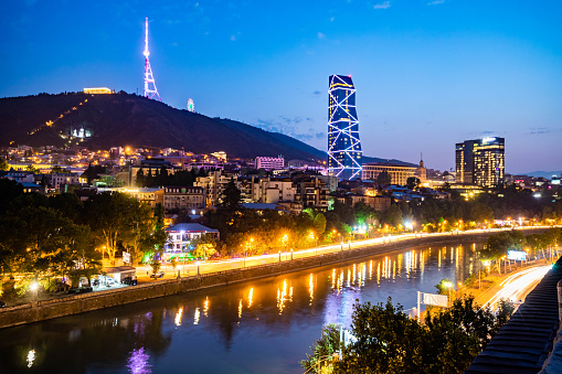 Colorful view of illuminated Mtkvari river in Tbilisi Georgia at night from above