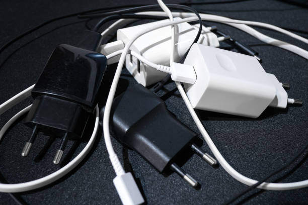 Pile of smartphone wired chargers on black surface,tech.