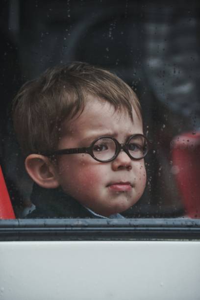 istock A little boy with round glasses looks through the bus window before leaving (vintage processing, noises, film photo) 1340347980