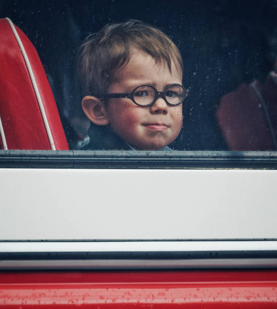 istock A little boy with round eyeglasses looks through the bus window (vintage tinting processing, noises, film photo) 1340347982