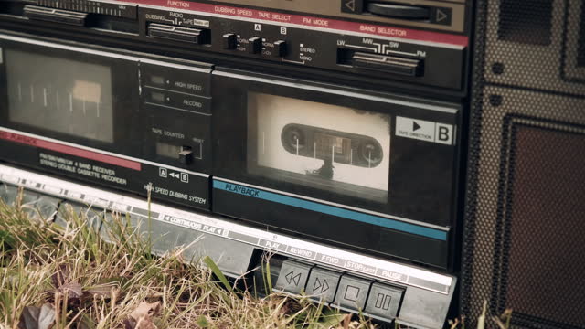 Small child turns on the play button on an old, retro tape recorder