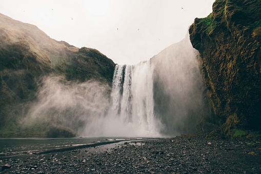 Majestic Skogafoss Waterfall under moody overcast cloudscape in summer. Falling water of the Skoga River. The Skógafoss is one of the biggest waterfalls in Iceland, with a width of 25m and a drop of 60m. Skógar, Rangárþing eystra, Southern Iceland, Sudurland, Iceland, Nordic Countries, Europe