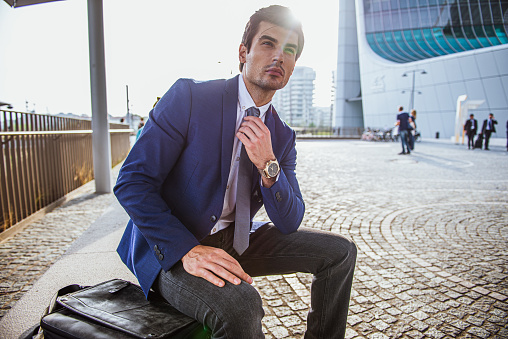 Side view of elegant businessman sitting in front of building