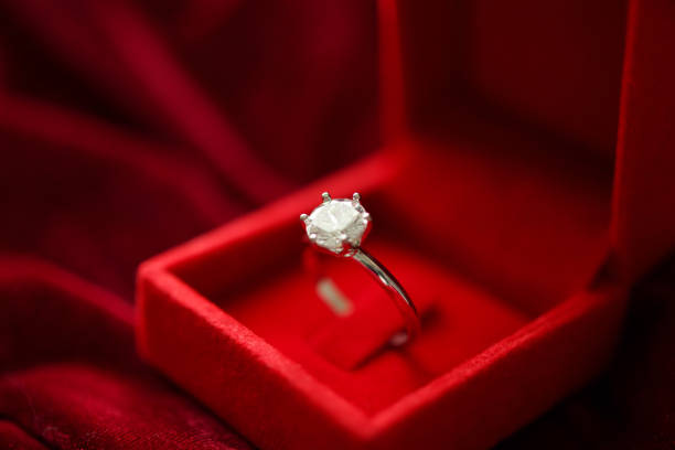 istock Diamond ring in jewelry gift box on red fabric background 1340367455