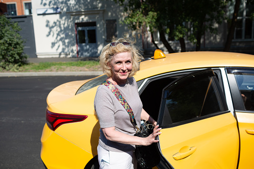 Elderly caucasian old aged woman take taxi car ride and opens vehicle door