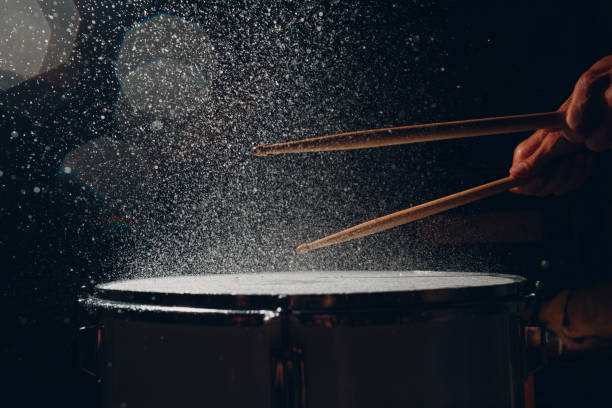 istock Drum sticks drumming beat rhythm on drum surface with splash water drops 1340367569
