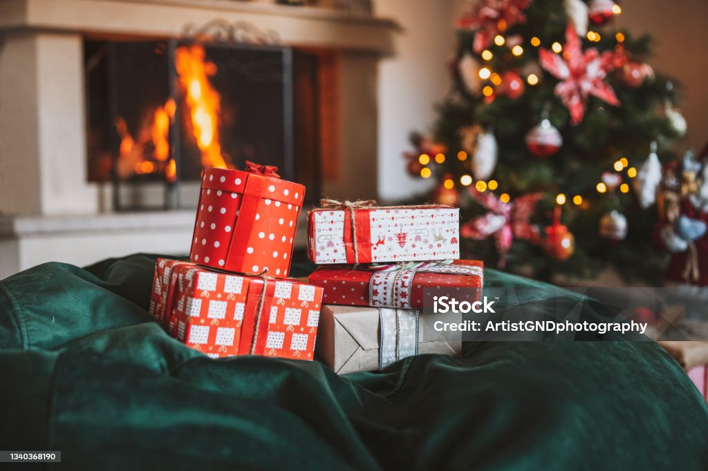 Cozy Christmas At Home. Stack of Christmas gifts in decorated home with Christmas tree and fireplace, Christmas background. Christmas Stocking Stock Photo