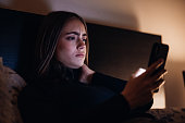 Bad News Young Woman Reading Messages on Mobile Phone lying in bed at night