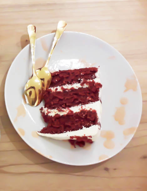 a very nice red velvet cake on a plate with two beautiful golden spoons