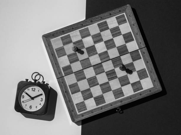 istock Black and white image of a chessboard with pieces and a clock on a black and white background. 1340385825