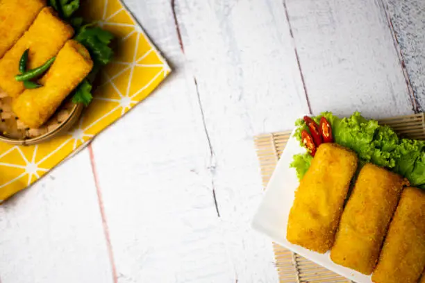 Delicious Risoles or Risol Vegetable is a typical Indonesian traditional street food made from flour skin, meat and vegetables stuffing inside, decorated with chilies and wooden table