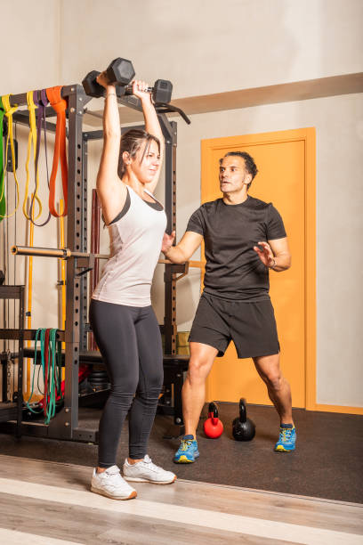 istock Woman doing shoulder exercise with dumbbells in the gym 1340386684
