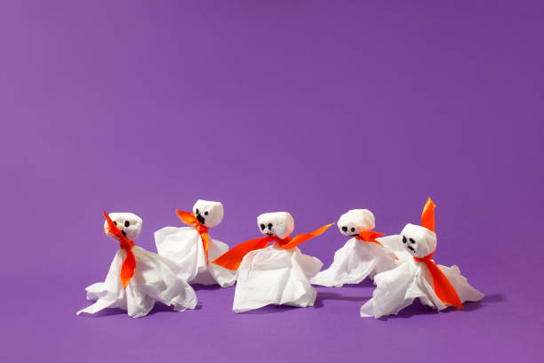 istock Halloween paper decorations on bright purple violet background. Black  ghosts from paper napkins. Halloween concept. Flat lay, top view, overhead. Party greeting card, invitation, flyer, banner 1340387853