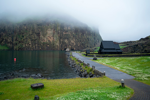 Old, black wooden church at the entrance to  Vestmannaeyjar harbor on the island of Heimaey, on Westman Islands.