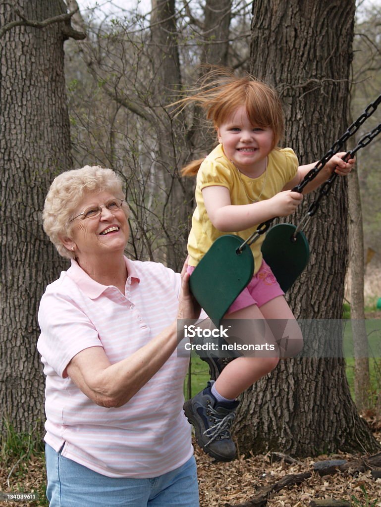 Swinging with Grandma A young girl being pushed on a swing by her grandmother.  Adolescence Stock Photo