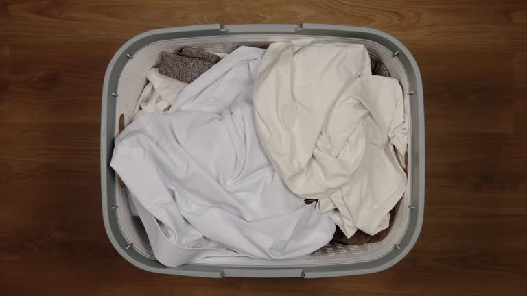 TOP VIEW: Many Dirty clothes fill a laundry basket on a floor - Stop Motion