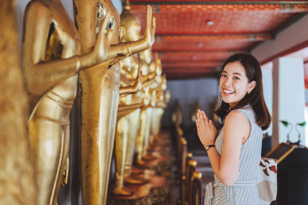 momento de relajación fin de semana tailandés / chino joven turista asiático alegre mujer haciendo sawasdee (orar) viajando rezando en la estatua en el templo wat pho bangkok, tailandia - religion buddha buddhism temple fotografías e imágenes de stock