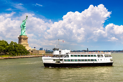 Statue of Liberty and tourist ship ferry in New York City, NY, USA