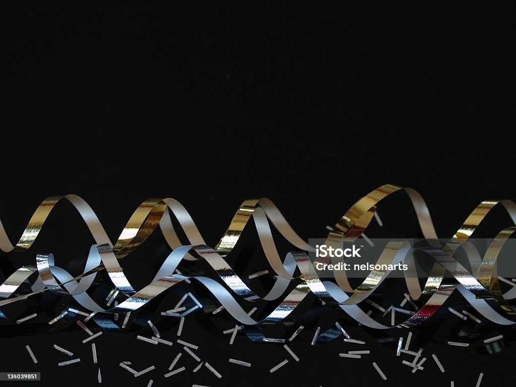 Silver and Gold Streamers on Black Silver and gold streamers with confetti on a black reflective background. Black Background Stock Photo