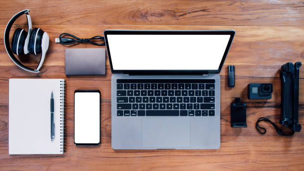 istock Top view with a digital camera, charger, headset, video camera, USB, personal laptop, book, pen, and electronics camera accessory technology concept on wooden background 1340402038